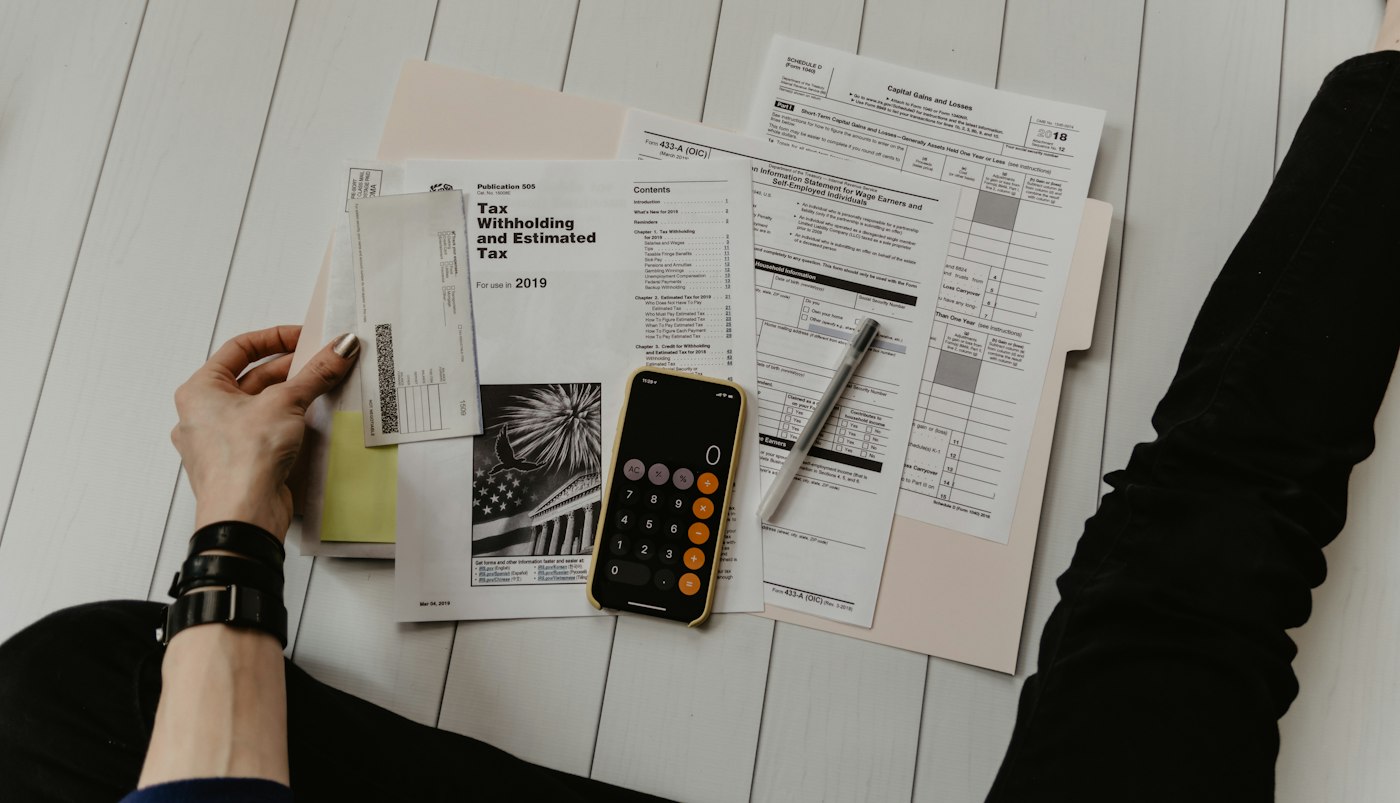 A calculator, ledger and bank statements laid out for a small-business cash-flow review